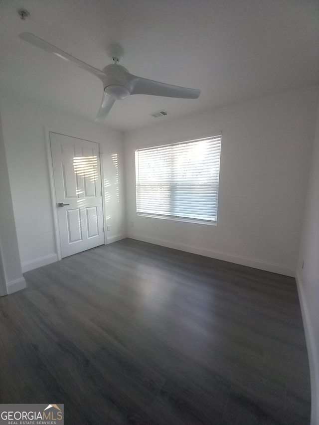 empty room featuring ceiling fan and dark wood-type flooring