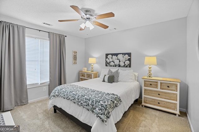 bedroom featuring multiple windows, a textured ceiling, carpet floors, and ceiling fan