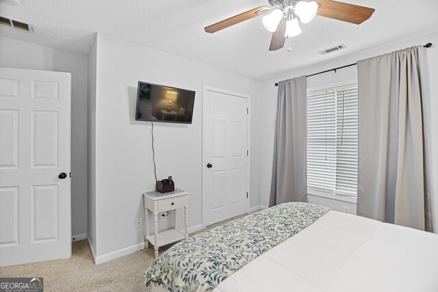 carpeted bedroom featuring ceiling fan, a textured ceiling, and multiple windows