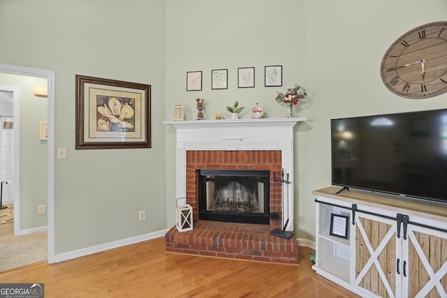 living room with hardwood / wood-style flooring and a brick fireplace