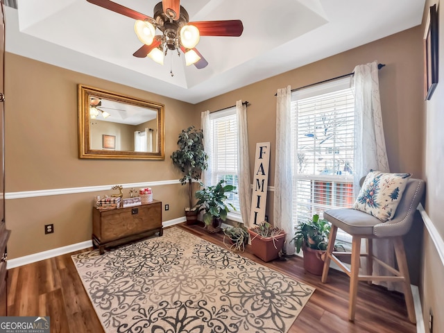 sitting room with a raised ceiling, ceiling fan, and hardwood / wood-style floors