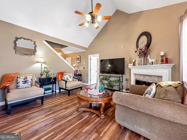 living room with hardwood / wood-style floors, ceiling fan, high vaulted ceiling, and a tile fireplace