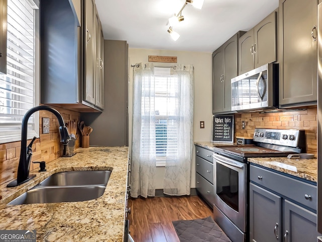 kitchen featuring sink, light stone countertops, appliances with stainless steel finishes, tasteful backsplash, and dark hardwood / wood-style flooring