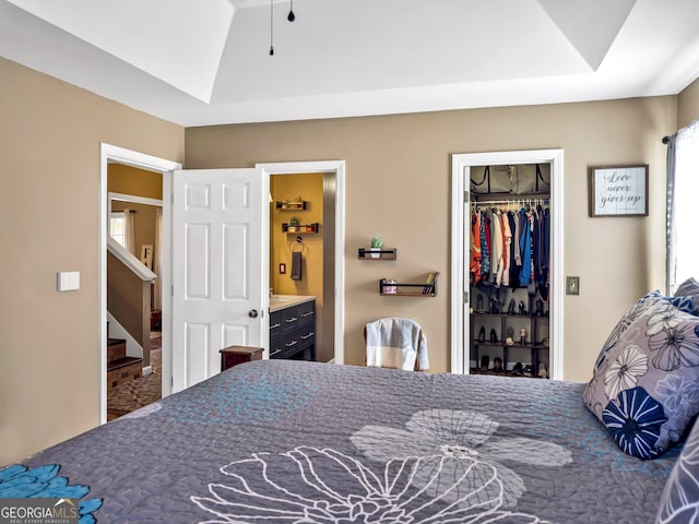 bedroom with a tray ceiling, ensuite bath, and a closet