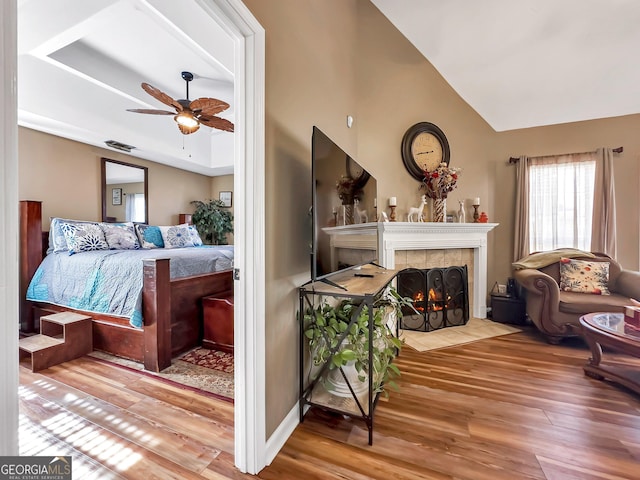 bedroom with ceiling fan, wood-type flooring, and a fireplace