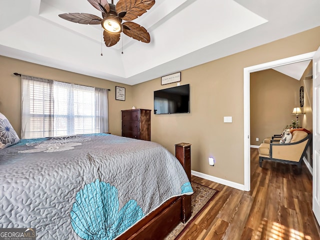 bedroom with a raised ceiling, ceiling fan, and dark hardwood / wood-style floors