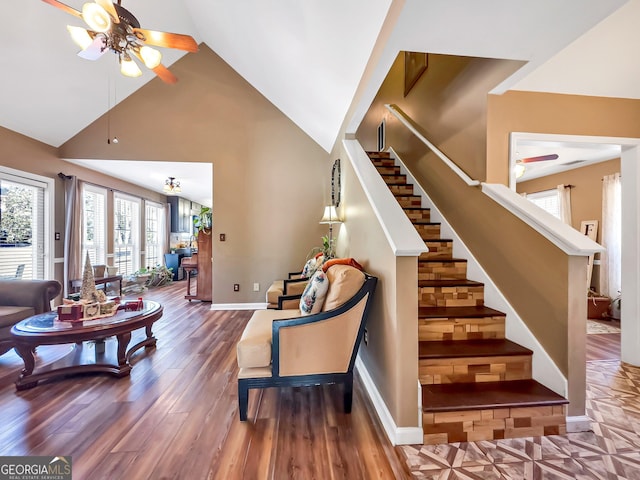 stairway featuring hardwood / wood-style floors, high vaulted ceiling, and ceiling fan