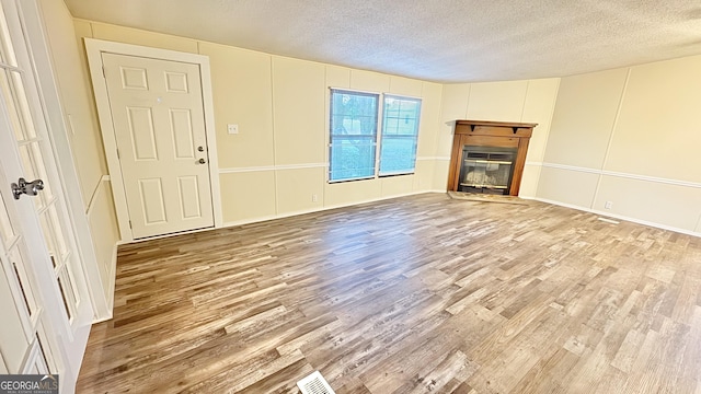 unfurnished living room featuring a textured ceiling and light hardwood / wood-style flooring