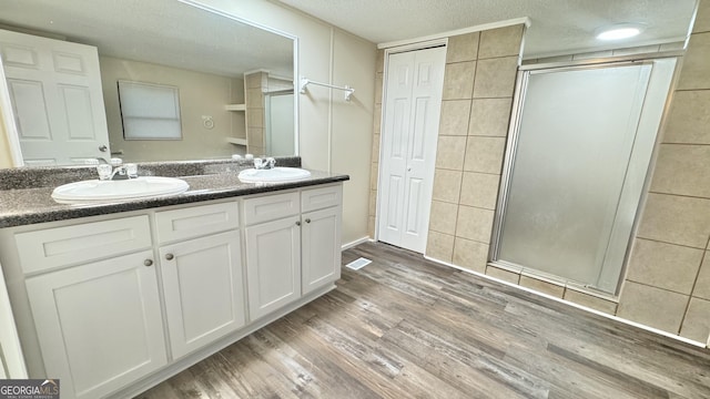 bathroom with a textured ceiling, vanity, an enclosed shower, and hardwood / wood-style flooring