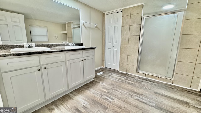 bathroom with walk in shower, vanity, a textured ceiling, and hardwood / wood-style flooring