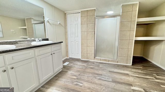 bathroom with hardwood / wood-style floors, vanity, an enclosed shower, and a textured ceiling