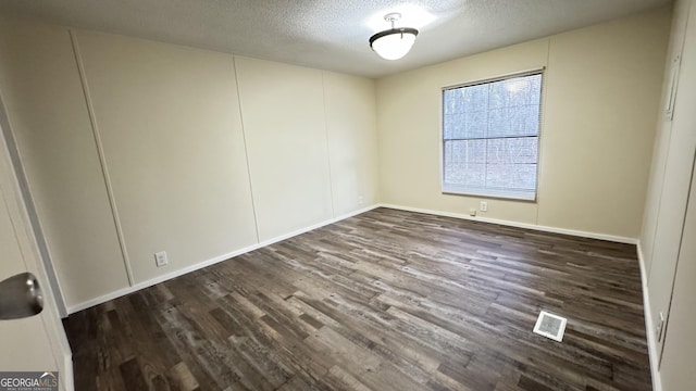 empty room with dark wood-type flooring and a textured ceiling