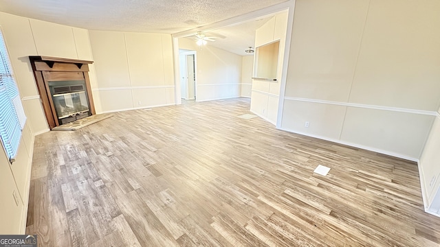 unfurnished living room featuring a textured ceiling, light wood-type flooring, ceiling fan, and lofted ceiling