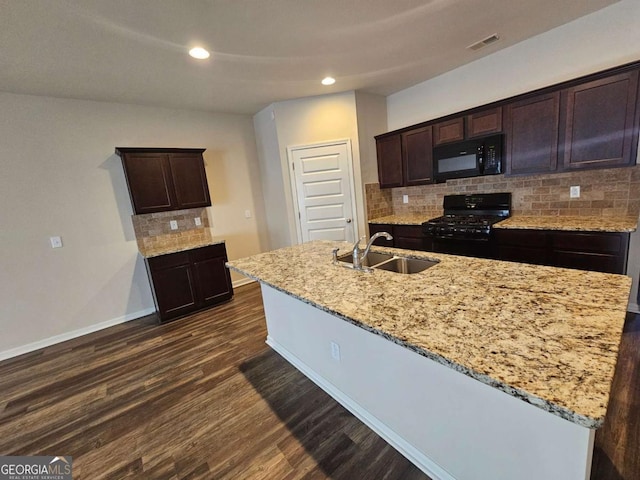 kitchen featuring dark brown cabinetry, sink, a kitchen island with sink, and black appliances