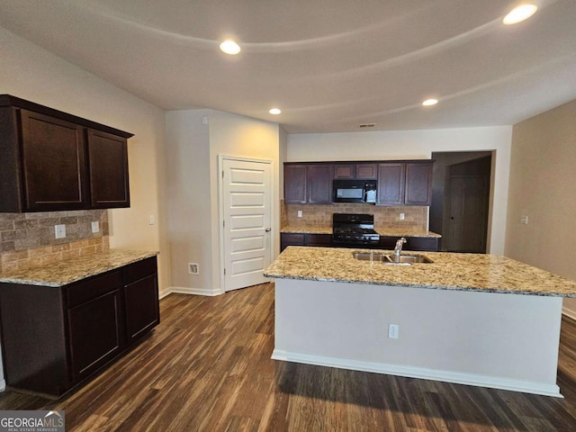 kitchen with backsplash, dark wood-type flooring, black appliances, an island with sink, and dark brown cabinets