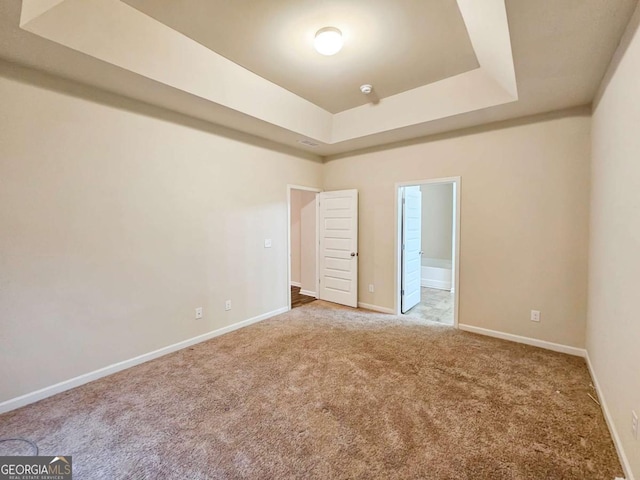 unfurnished bedroom with carpet and a tray ceiling