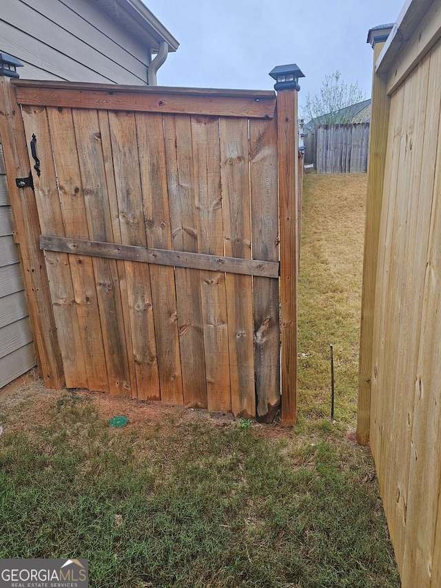 view of gate with a lawn