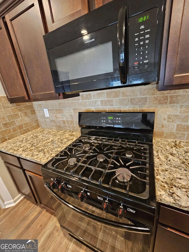 kitchen with black appliances, dark brown cabinets, light stone countertops, and tasteful backsplash