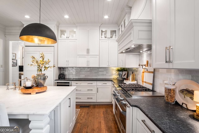 kitchen featuring decorative light fixtures, backsplash, double oven range, white cabinets, and dark stone counters