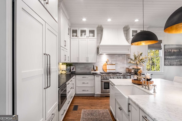 kitchen featuring dark wood-type flooring, pendant lighting, white cabinets, and custom range hood