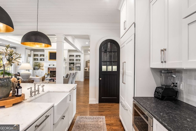 kitchen with dark wood-type flooring, light stone counters, white cabinetry, and pendant lighting