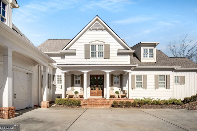 view of property with covered porch, a garage, and french doors