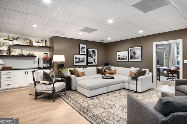 living room with light hardwood / wood-style floors and a drop ceiling