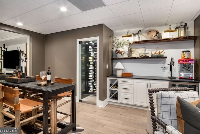 bar with light wood-type flooring and white cabinetry