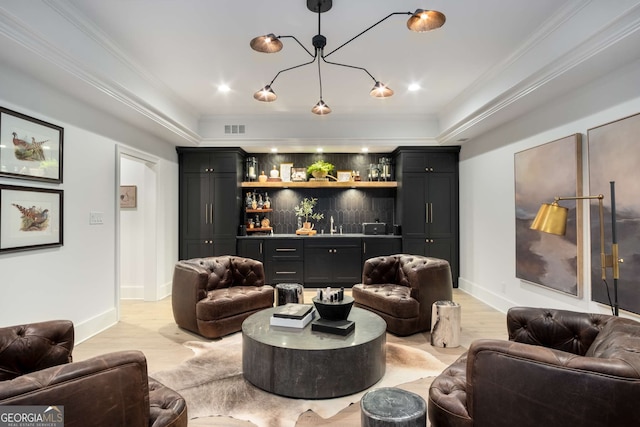 living room featuring bar, ornamental molding, light hardwood / wood-style flooring, and a raised ceiling