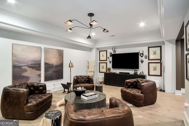 living room with a notable chandelier, ornamental molding, and light hardwood / wood-style floors