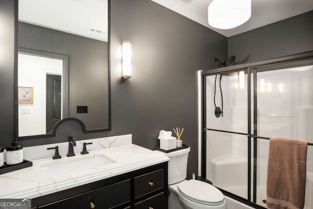 bathroom with toilet, vanity, and a shower with door