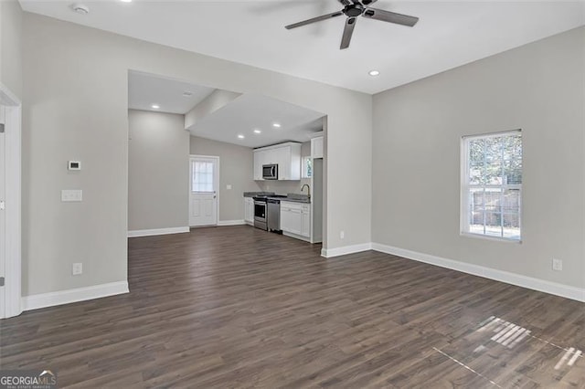 unfurnished living room with ceiling fan, a healthy amount of sunlight, dark hardwood / wood-style flooring, and vaulted ceiling