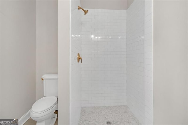 bathroom with a tile shower and toilet