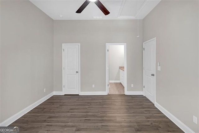 unfurnished bedroom with a high ceiling, connected bathroom, ceiling fan, and dark wood-type flooring