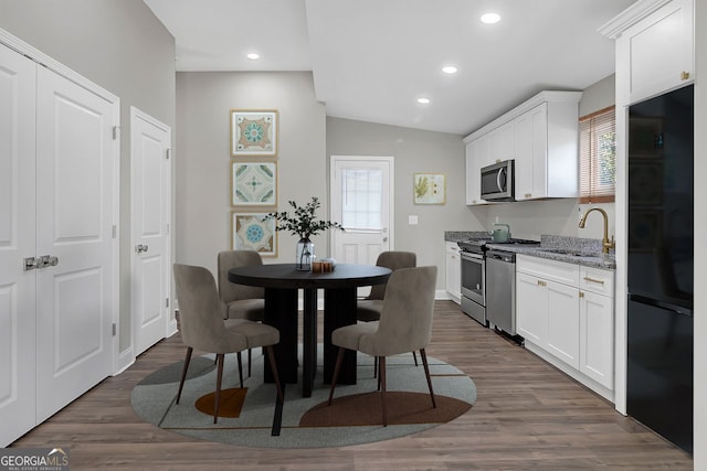 dining space with vaulted ceiling, sink, and dark wood-type flooring