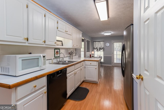 kitchen with white cabinetry, dishwasher, sink, stainless steel fridge, and a textured ceiling