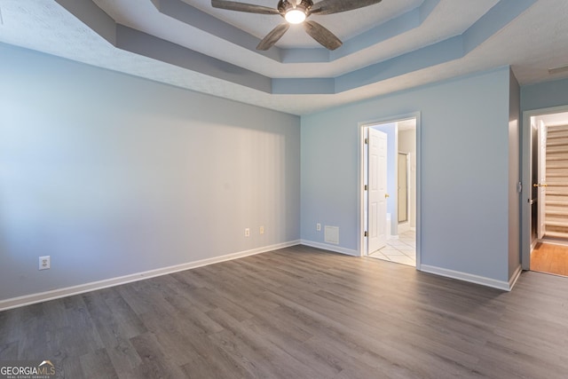 spare room featuring hardwood / wood-style flooring, a raised ceiling, and ceiling fan