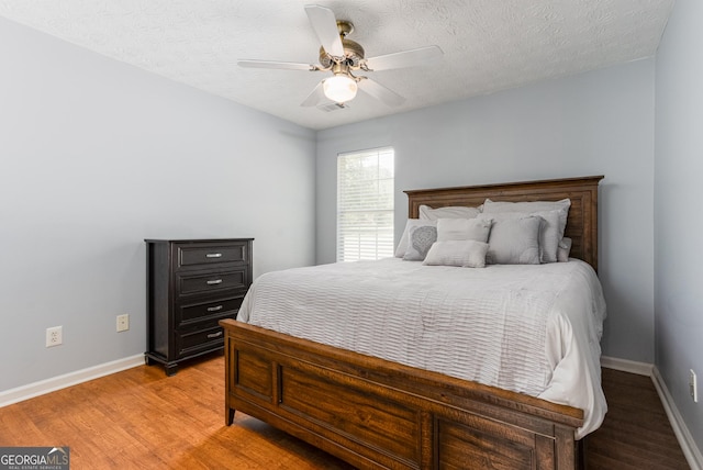 bedroom with a textured ceiling, hardwood / wood-style flooring, and ceiling fan