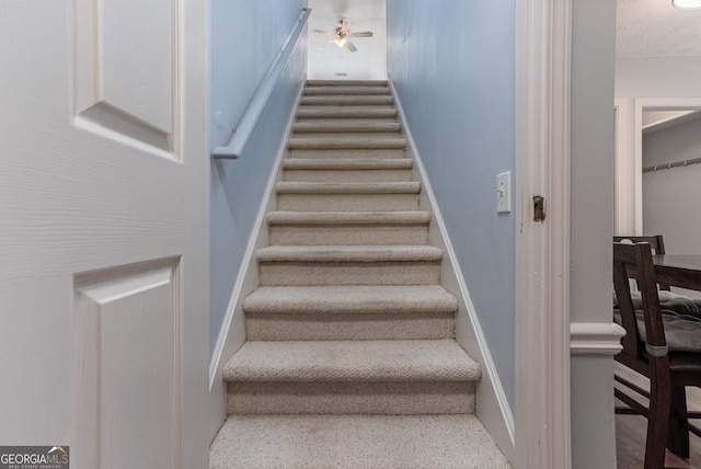 staircase featuring a textured ceiling and ceiling fan