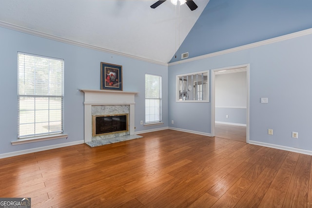 unfurnished living room featuring a high end fireplace, a wealth of natural light, hardwood / wood-style floors, and ceiling fan