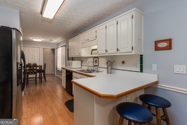 kitchen featuring a kitchen breakfast bar, stainless steel fridge with ice dispenser, kitchen peninsula, a textured ceiling, and white cabinets