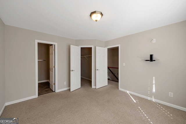 unfurnished bedroom featuring carpet, ensuite bathroom, a walk in closet, and a closet