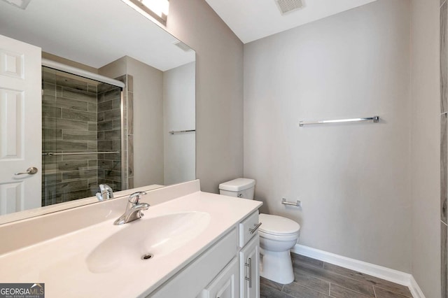 bathroom featuring vanity, toilet, and a shower with door