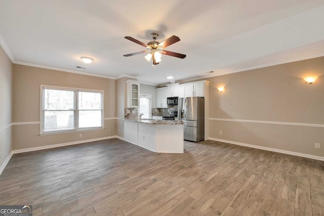 kitchen featuring white cabinetry, light stone counters, backsplash, kitchen peninsula, and appliances with stainless steel finishes