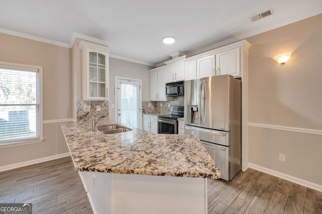 kitchen featuring kitchen peninsula, appliances with stainless steel finishes, ornamental molding, sink, and white cabinets