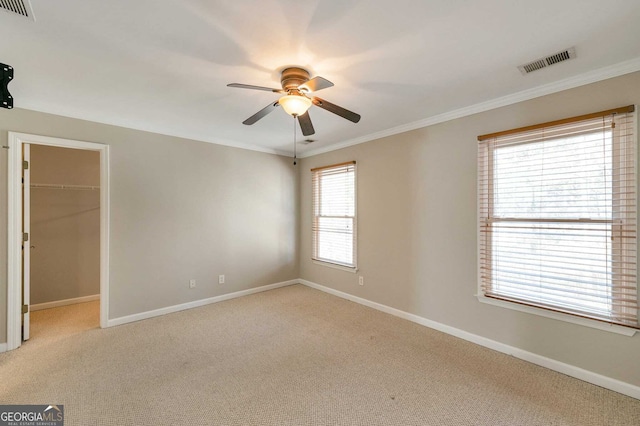 spare room with light carpet, ceiling fan, and ornamental molding