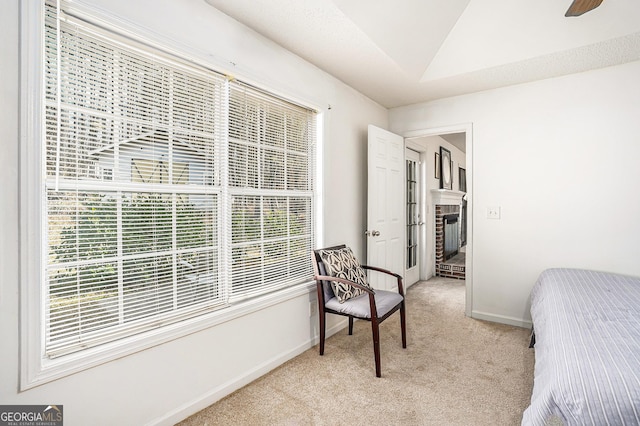 bedroom featuring ceiling fan, a fireplace, light carpet, and vaulted ceiling