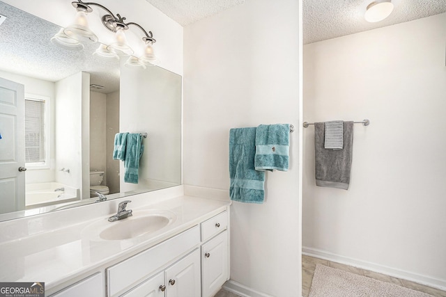 bathroom with vanity, toilet, a textured ceiling, and a washtub