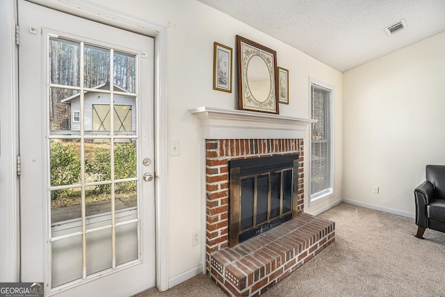 carpeted living room with a textured ceiling and a brick fireplace