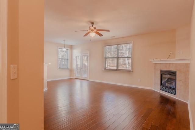 unfurnished living room featuring hardwood / wood-style flooring, a tile fireplace, and plenty of natural light